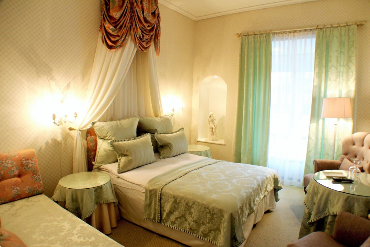 A room with a bed, a chair, a small table, and a lamp.