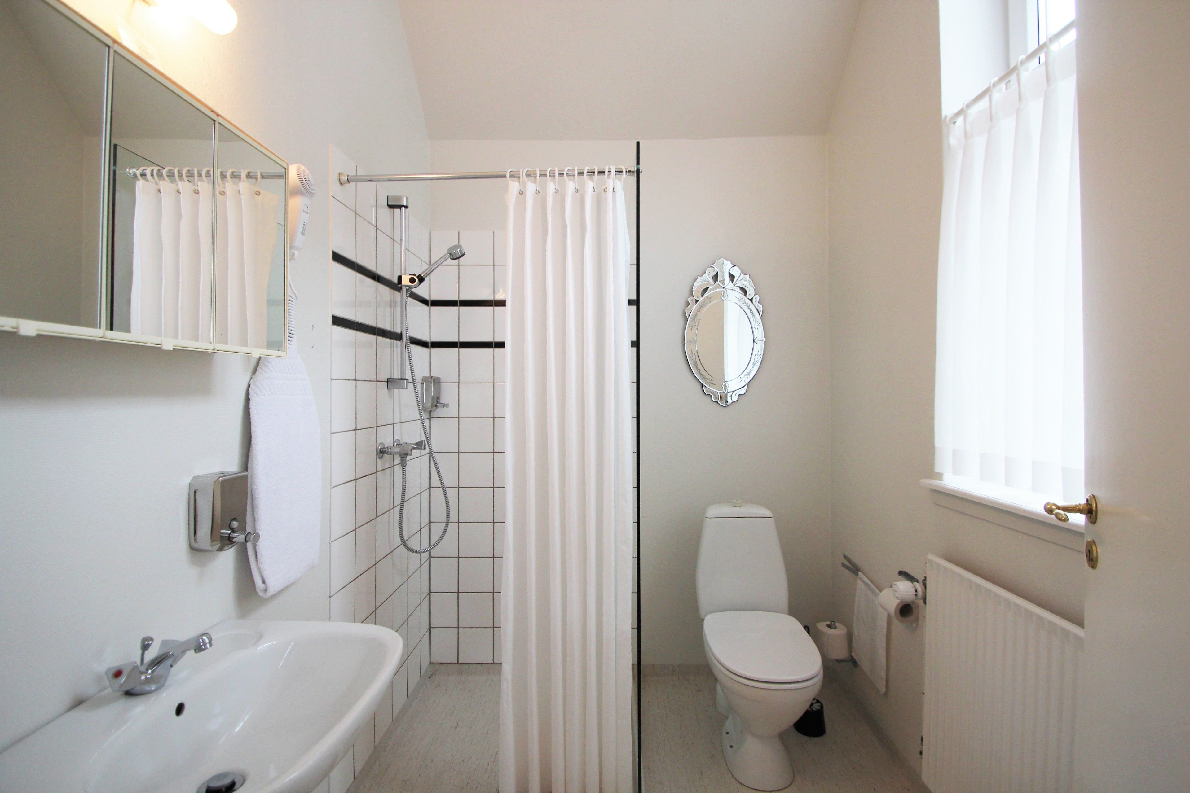 A bathroom with a shower, toilet, sink, and a mirror.