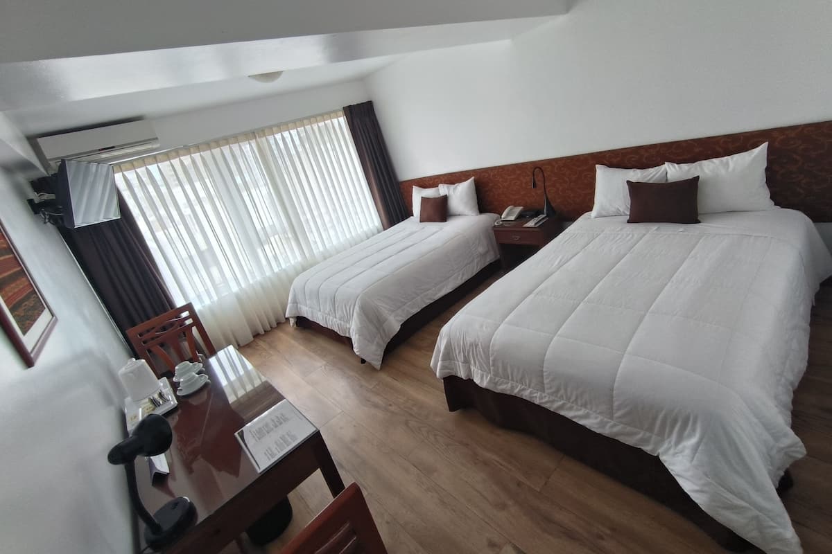 A hotel room with two beds, a desk, and a chair.