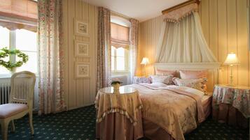 Une chambre à coucher avec un lit à baldaquin, des rideaux à motifs floraux, une table ronde et une chaise.
