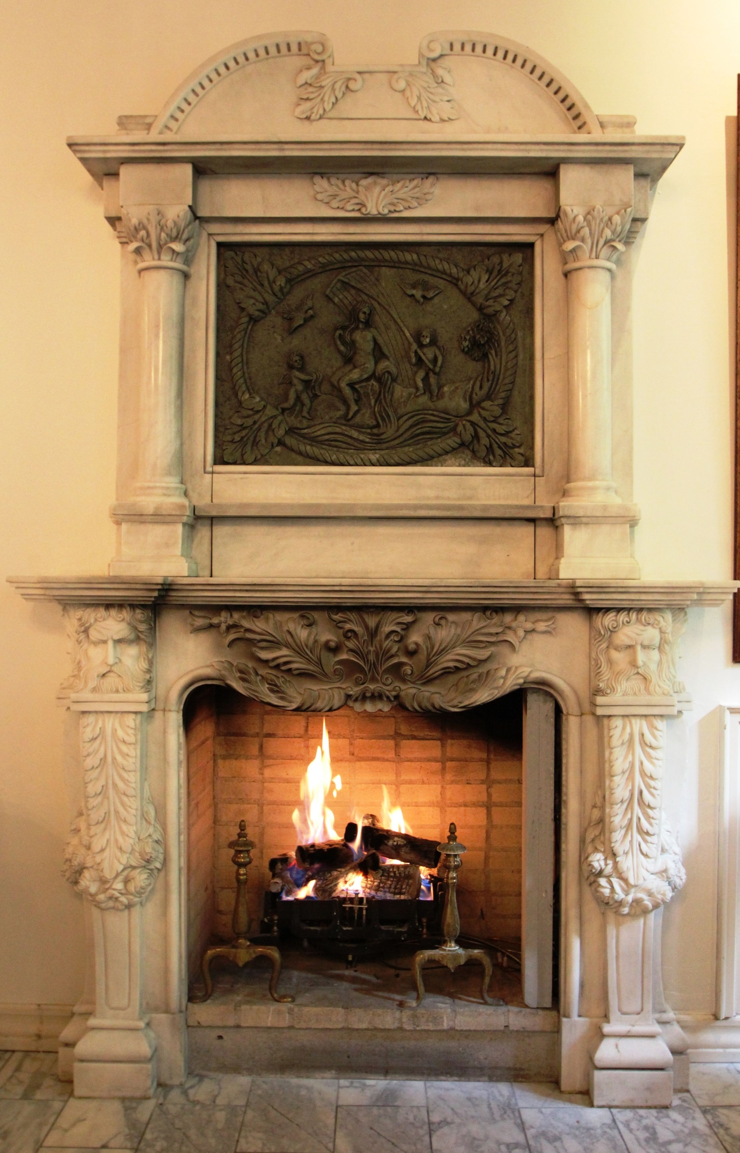 Una chimenea con elaboradas tallas y fuego encendido.