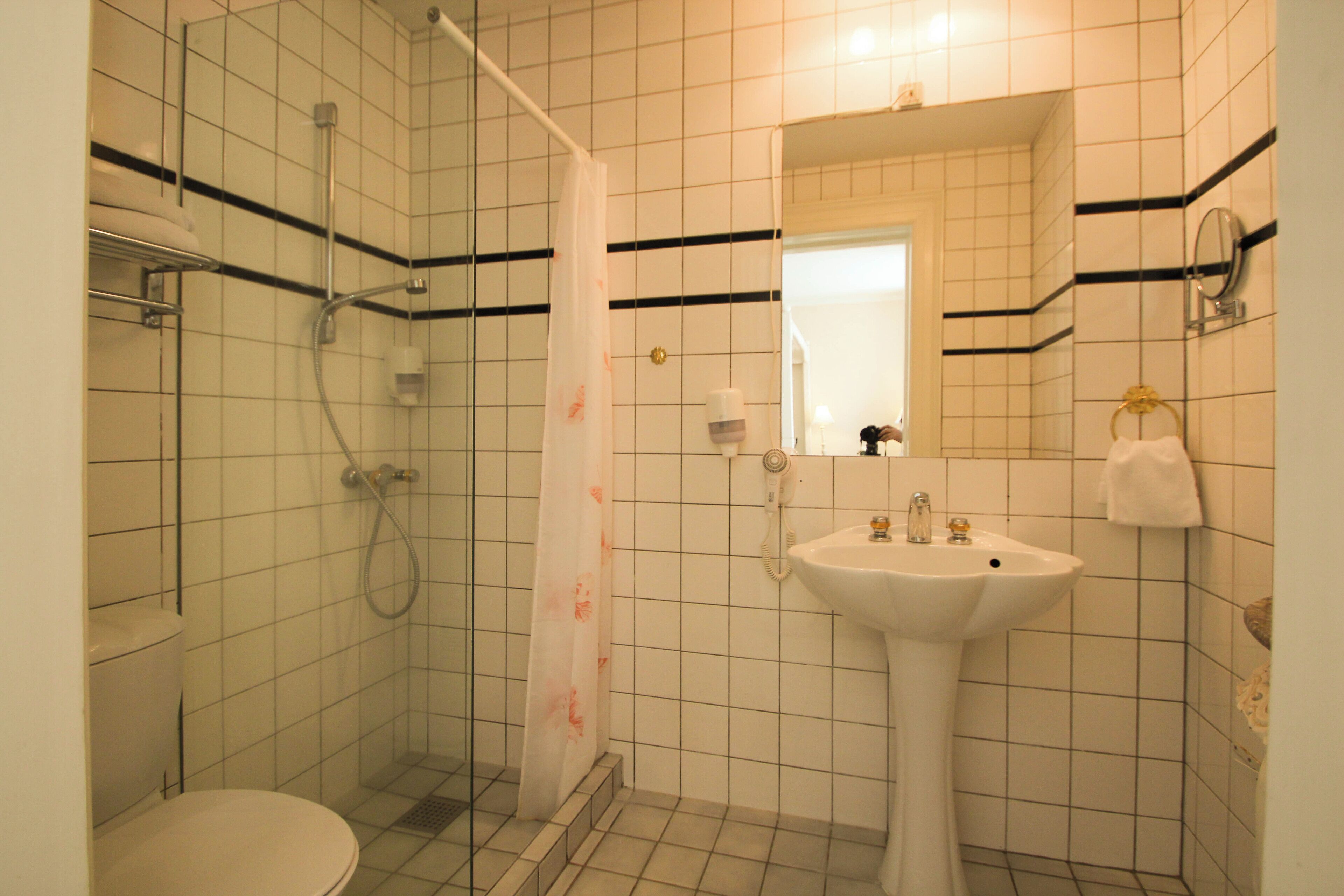 Un baño con inodoro, ducha con cortina, lavabo y espejo.