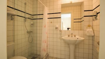 Un baño con inodoro, ducha con cortina, lavabo y espejo.