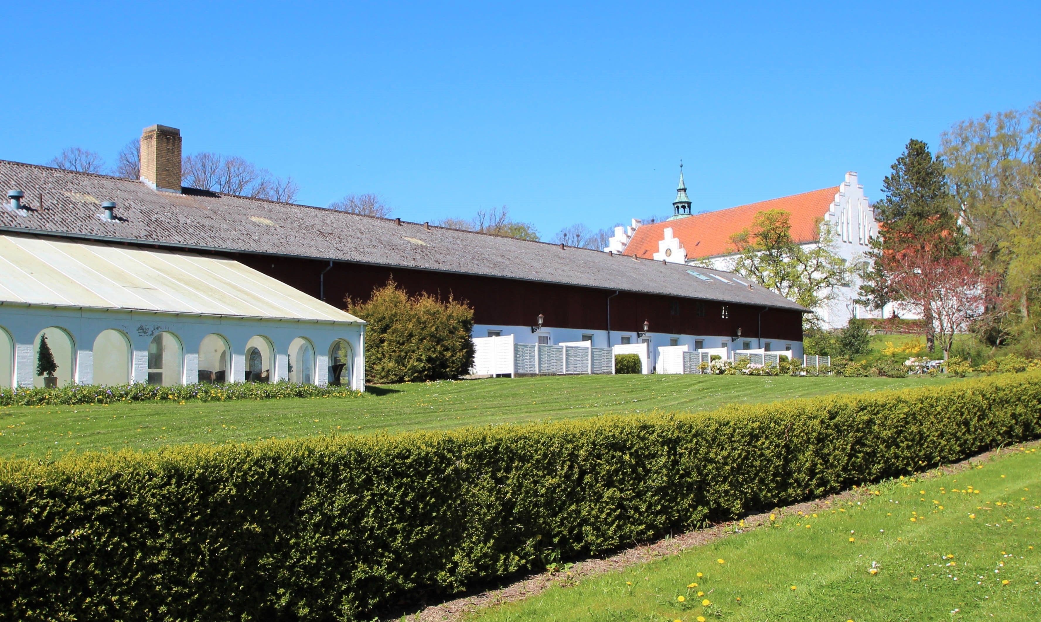 A large building with a long, covered corridor and a separate section with arched windows.