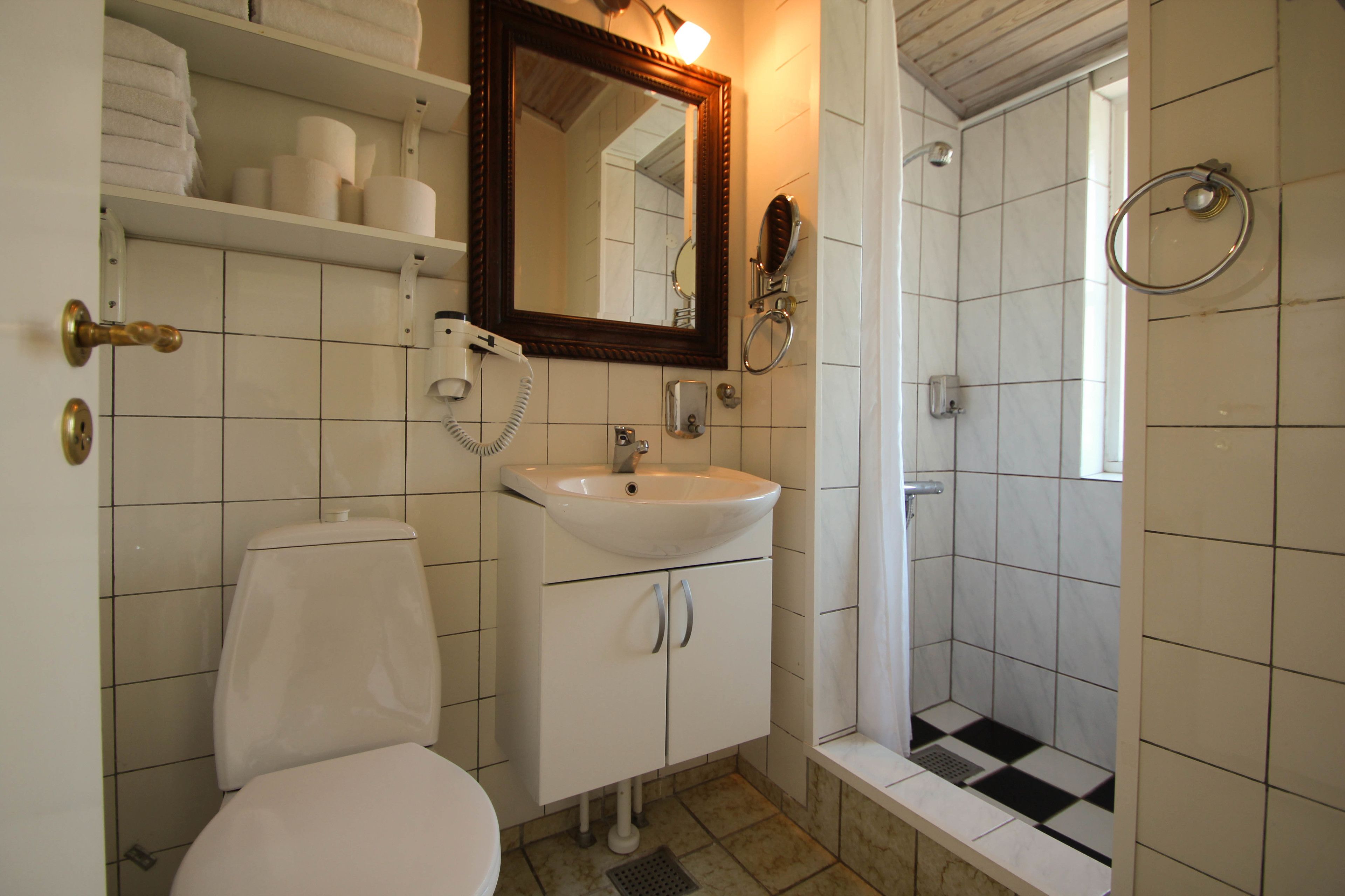 A bathroom with a toilet, sink, mirror, and shower.