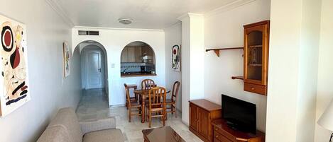 A living room with a sofa, TV stand, and dining area.