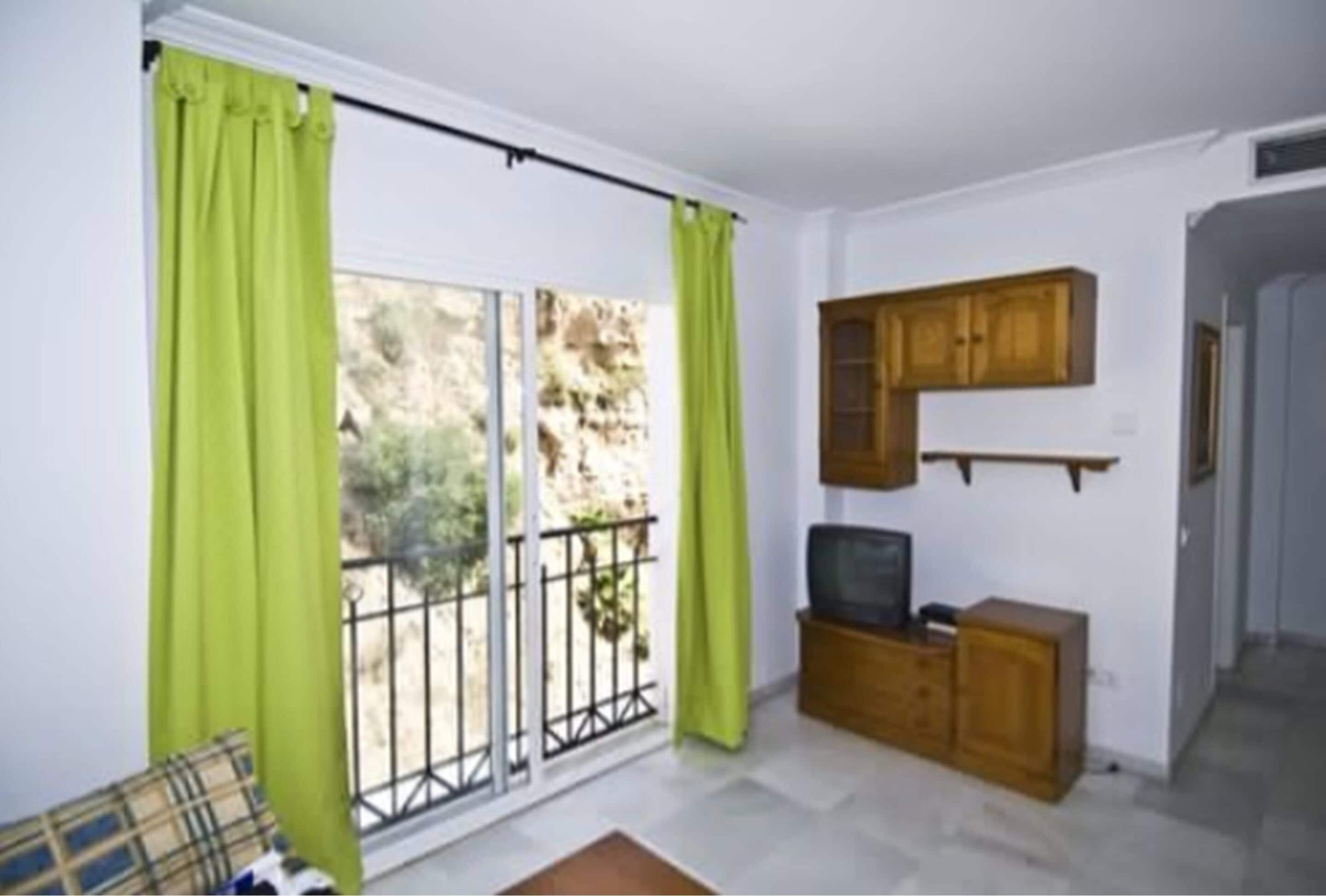 Una habitación con puerta corrediza de vidrio, un mueble de madera y un televisor.