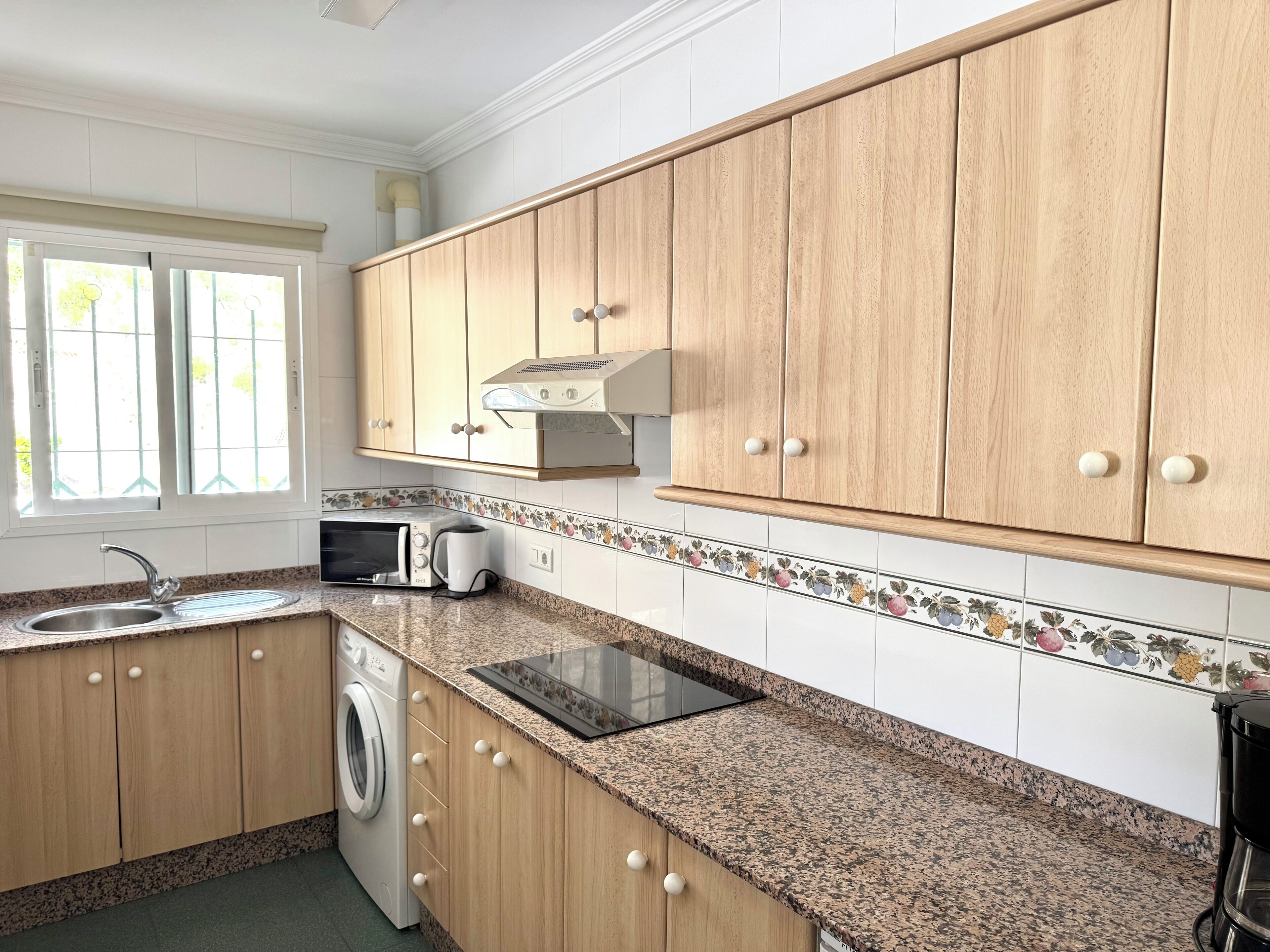 A kitchen with wooden cabinets, a washing machine, a microwave, and a toaster.