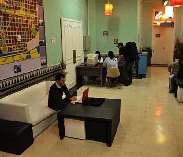 A lobby with a reception desk, a sofa, and a coffee table. - Adventure Hostel (Buenos Aires)