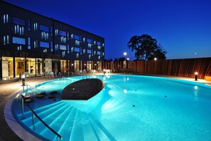 Una piscina con un edificio moderno al fondo, rodeada por una valla de madera.