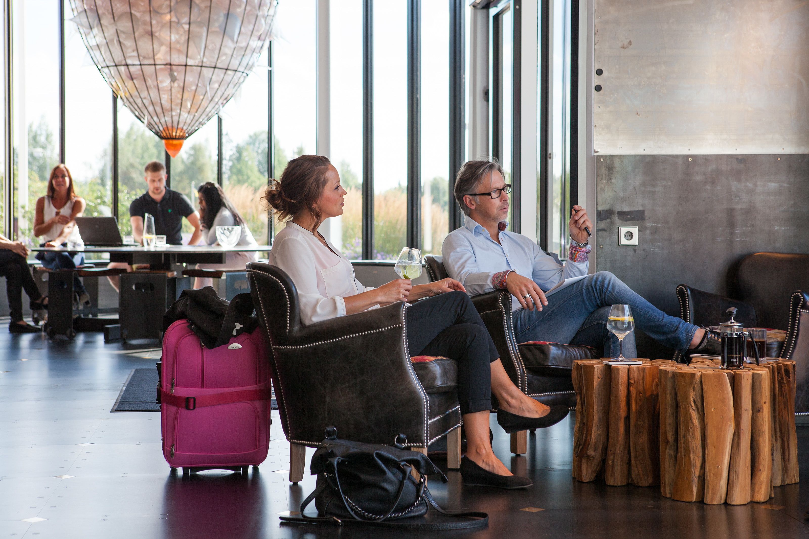 A modern lounge area with leather seating, a coffee table, and a view through large windows.
