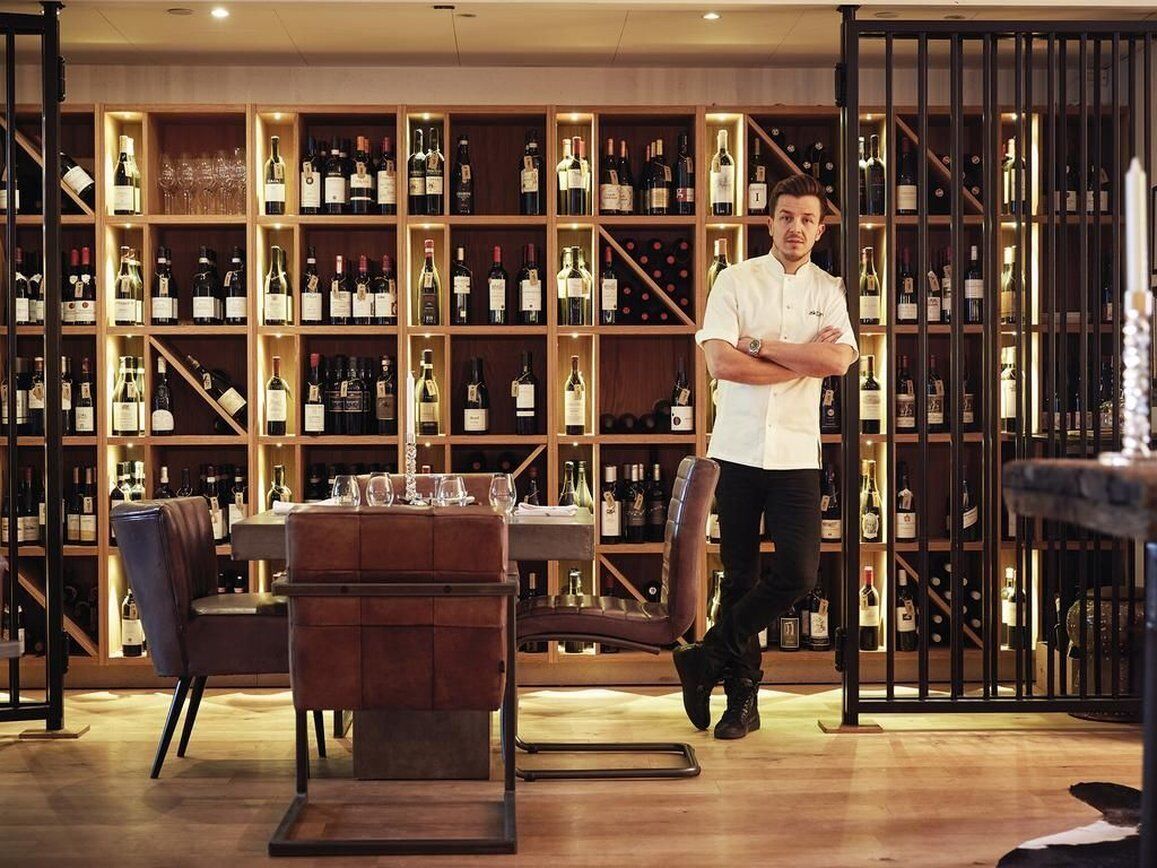 A wine cellar with wooden shelves and a dining area with a table and chairs.