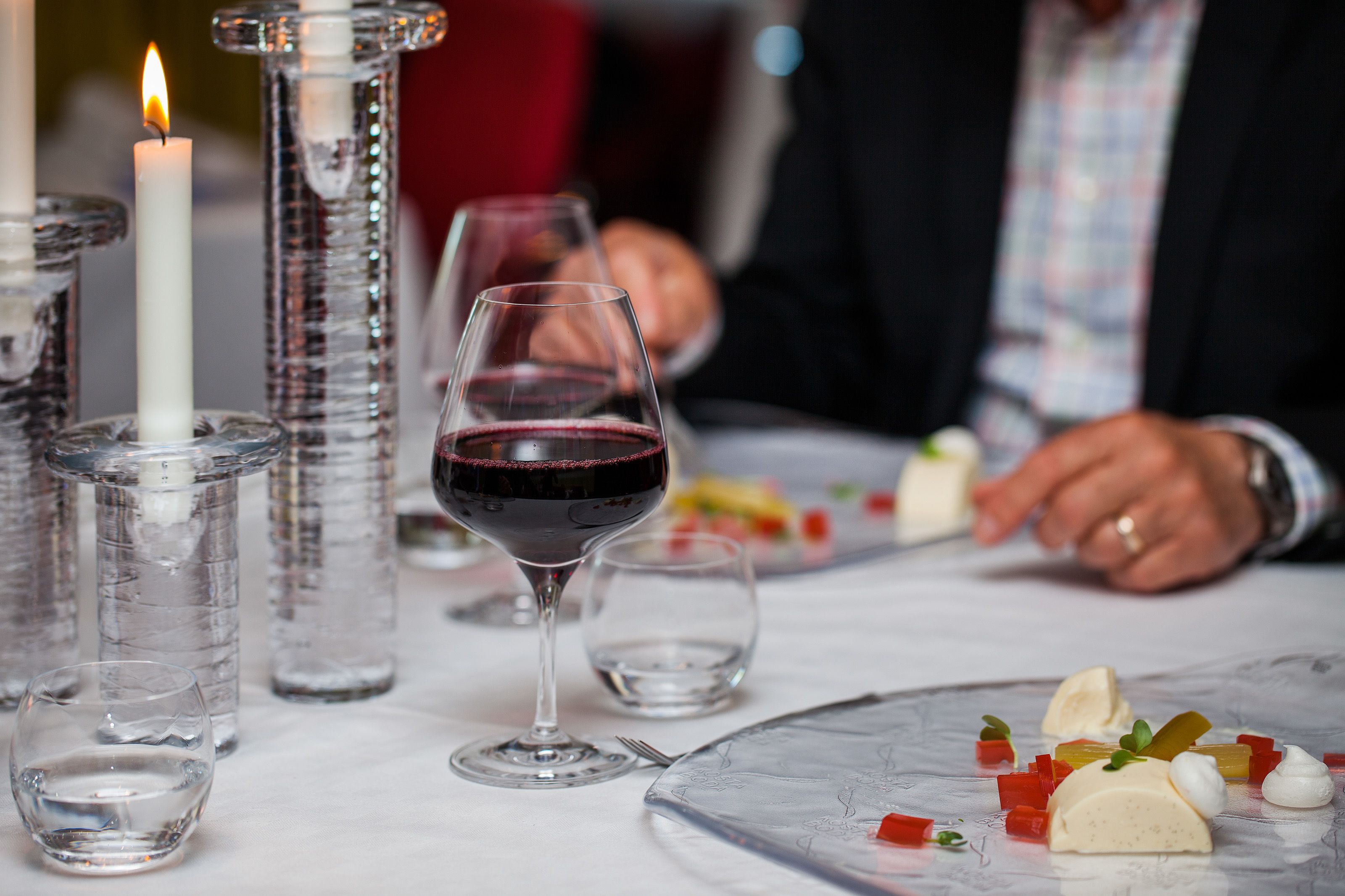 A dining table with a candle, wine glass, and clear glassware.