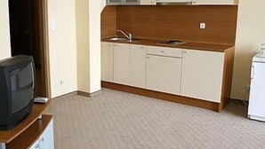 A compact kitchen with white cabinets, a wooden countertop, a sink, and a small refrigerator. - Palm Beach (Varna)