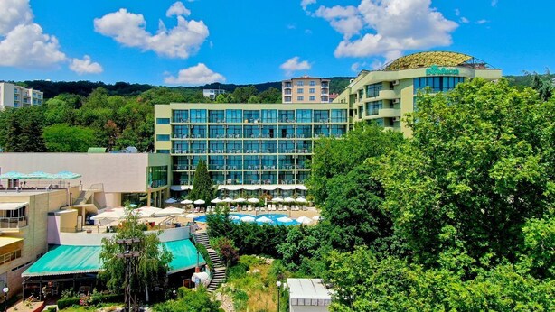 Un hotel con varios pisos, piscina y una zona exterior techada.