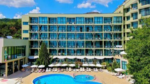 Un hotel de varios pisos con piscina, zona de estar al aire libre y vistas del paisaje circundante.