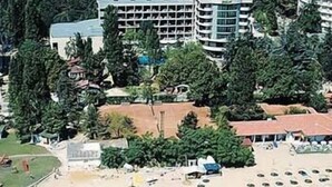 Un complejo turístico en la playa con varias construcciones, una playa de arena y una vista despejada del océano.