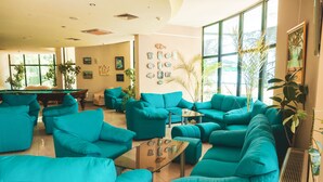 A spacious living area with teal sofas, a pool table, and large windows offering natural light. - Palm Beach (Varna)