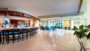 Un vestíbulo con zona de bar, asientos y ventanas amplias.
