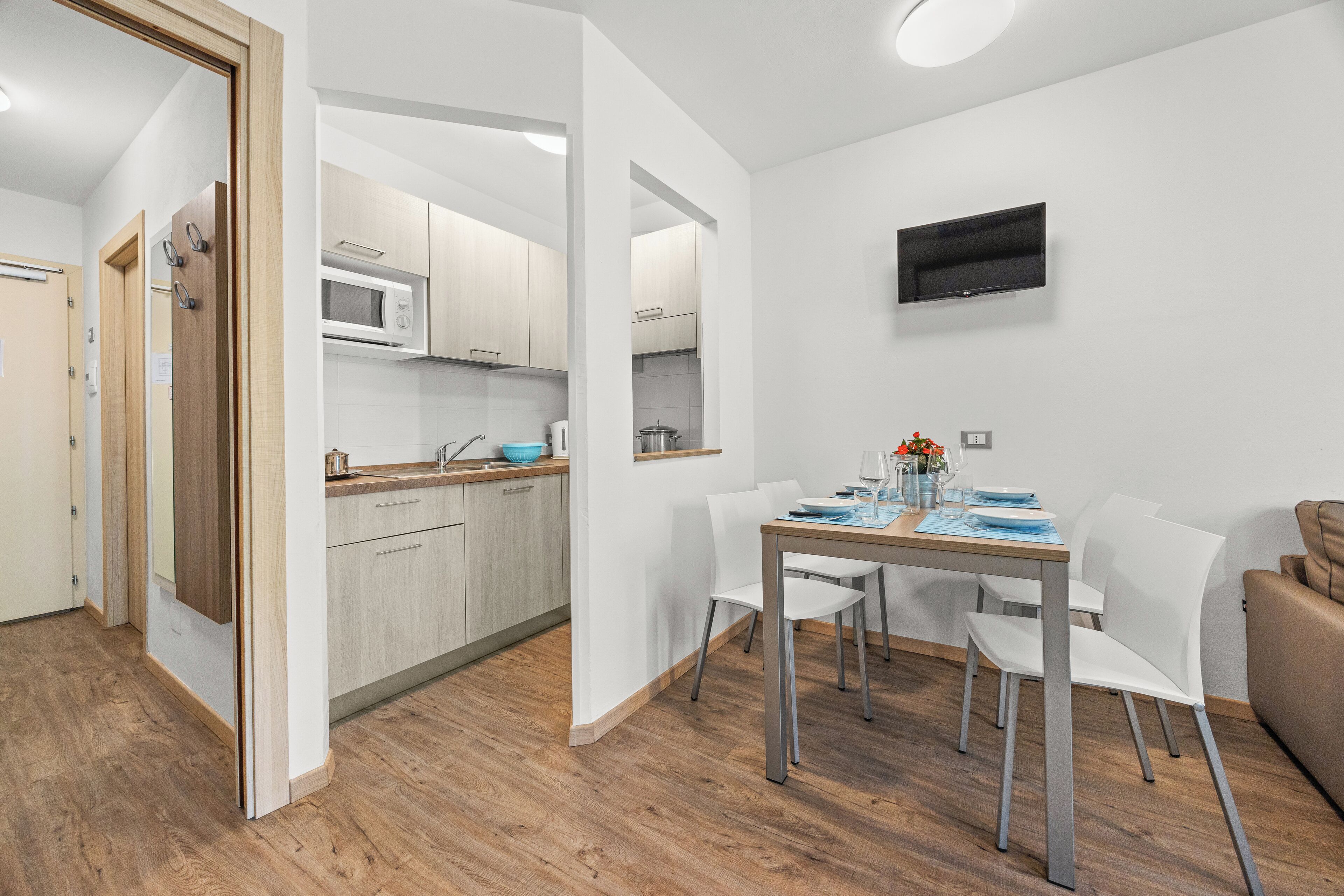 A modern kitchen with white cabinets, a microwave, and a dining area with a table and chairs.