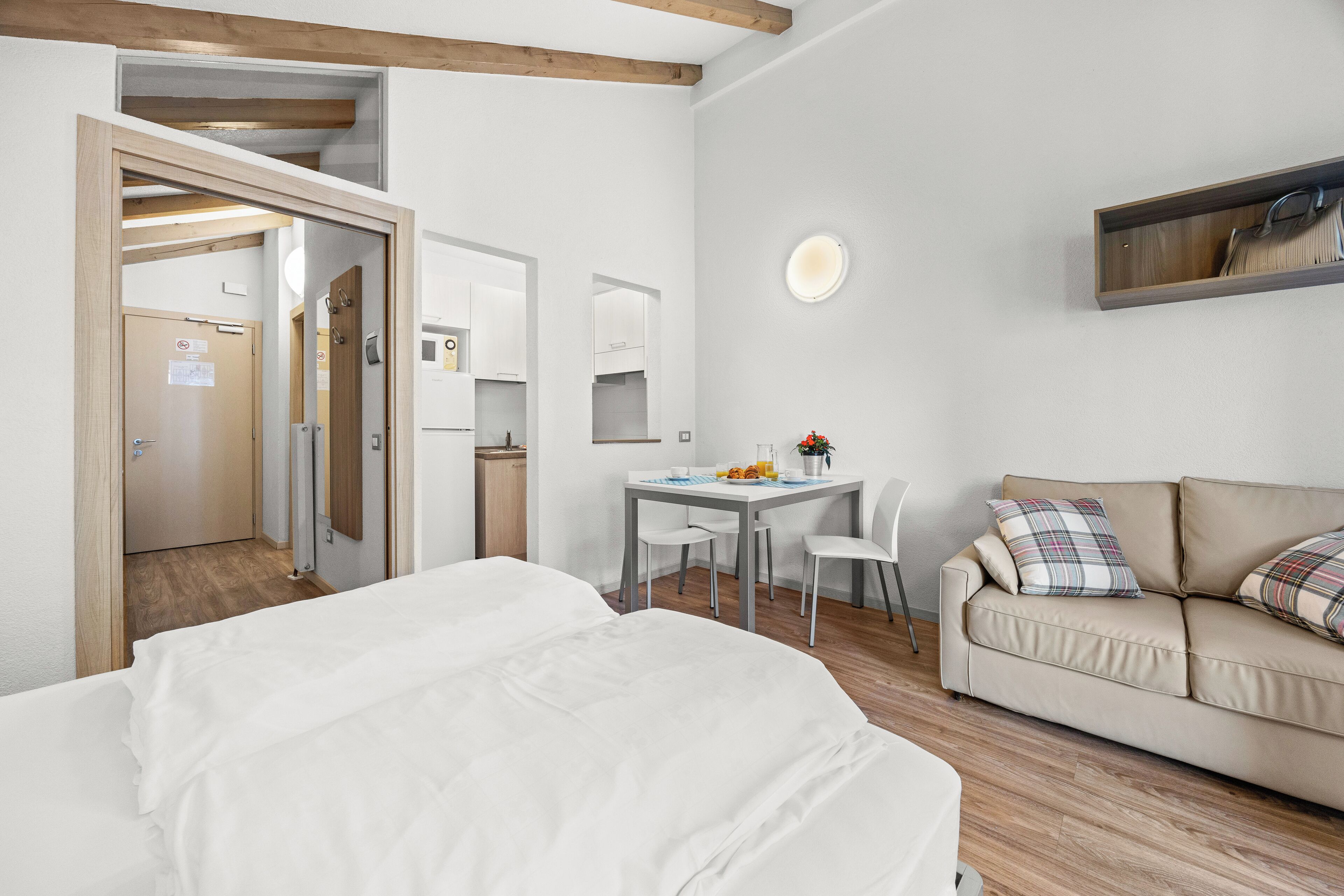 Una habitación de hotel con cama, sofá, escritorio y sillas, y un espejo.