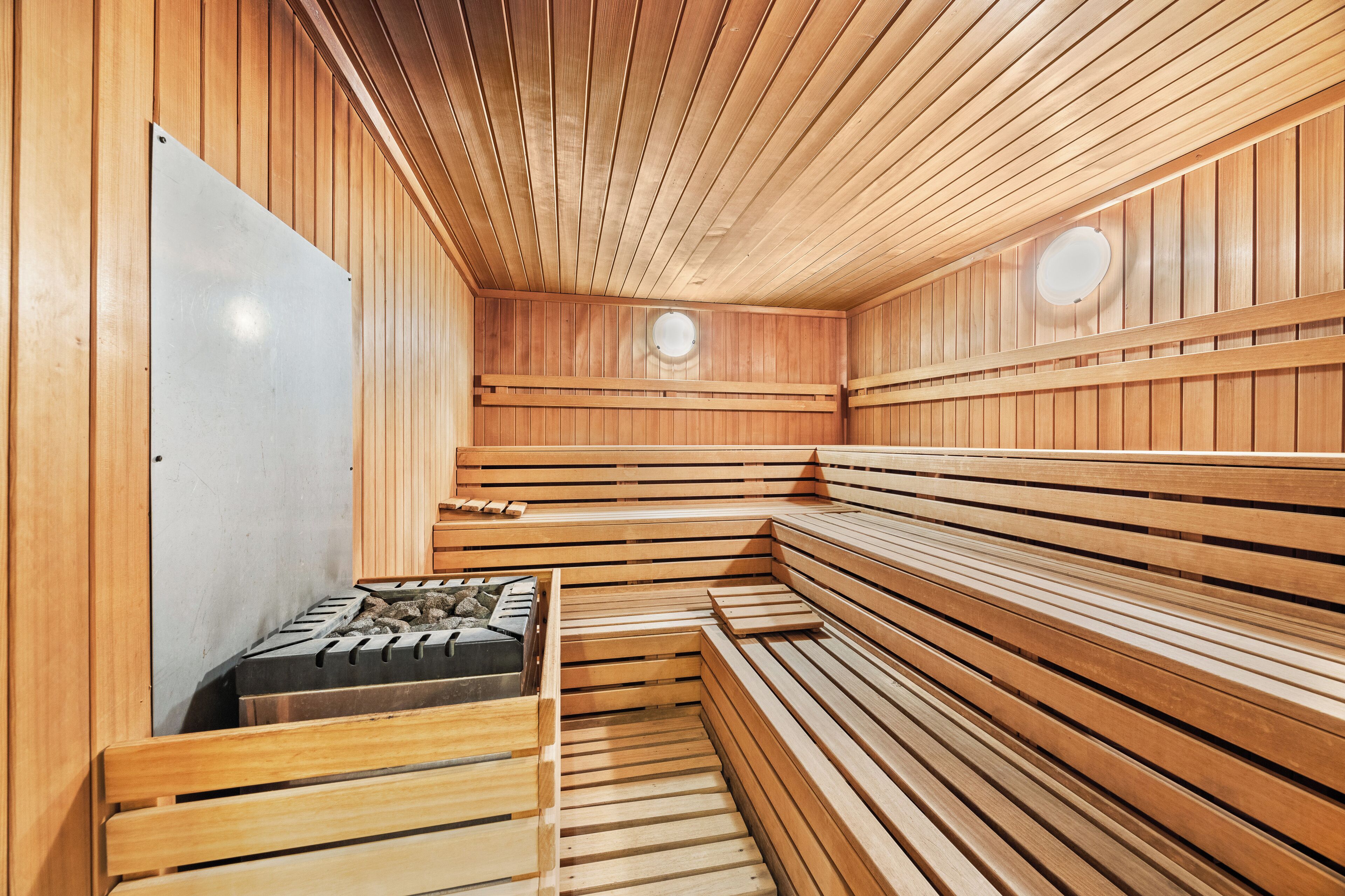 Un sauna avec des bancs en bois et un banc équipé d’un fauteuil de massage.