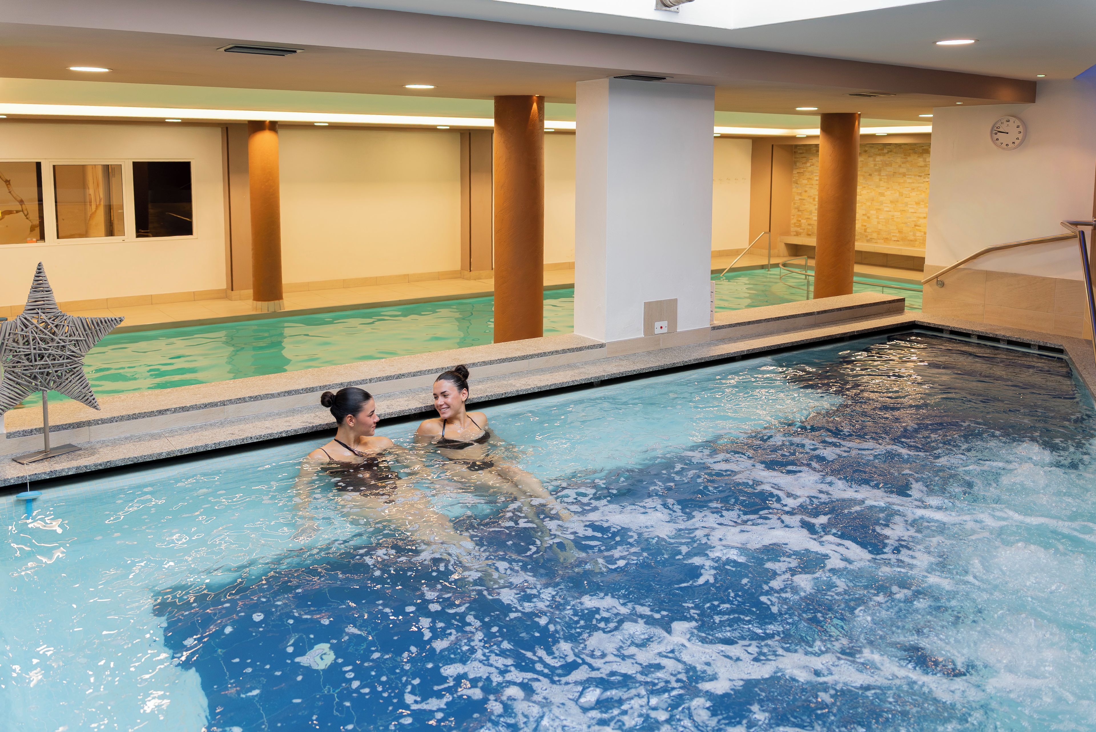 An indoor swimming pool with clear water, a star-shaped decoration, and a clock on the wall.