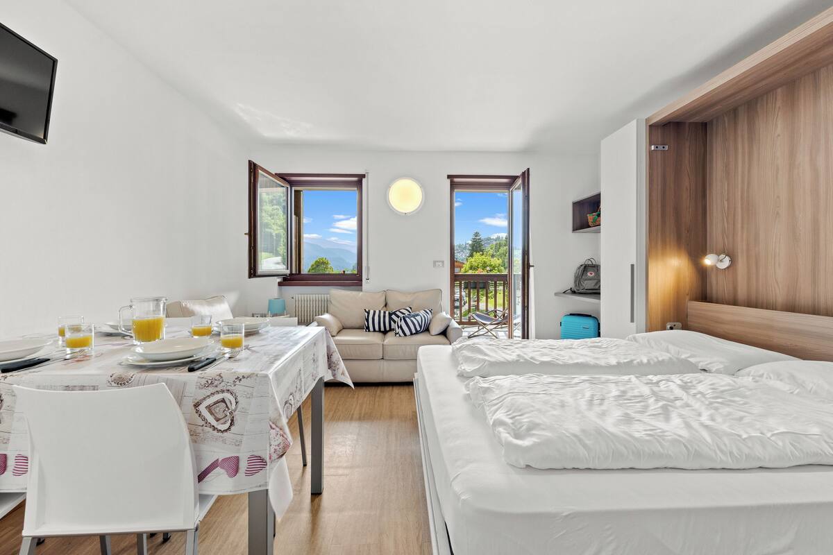 A modern room with a dining area, a sofa, and a bed.