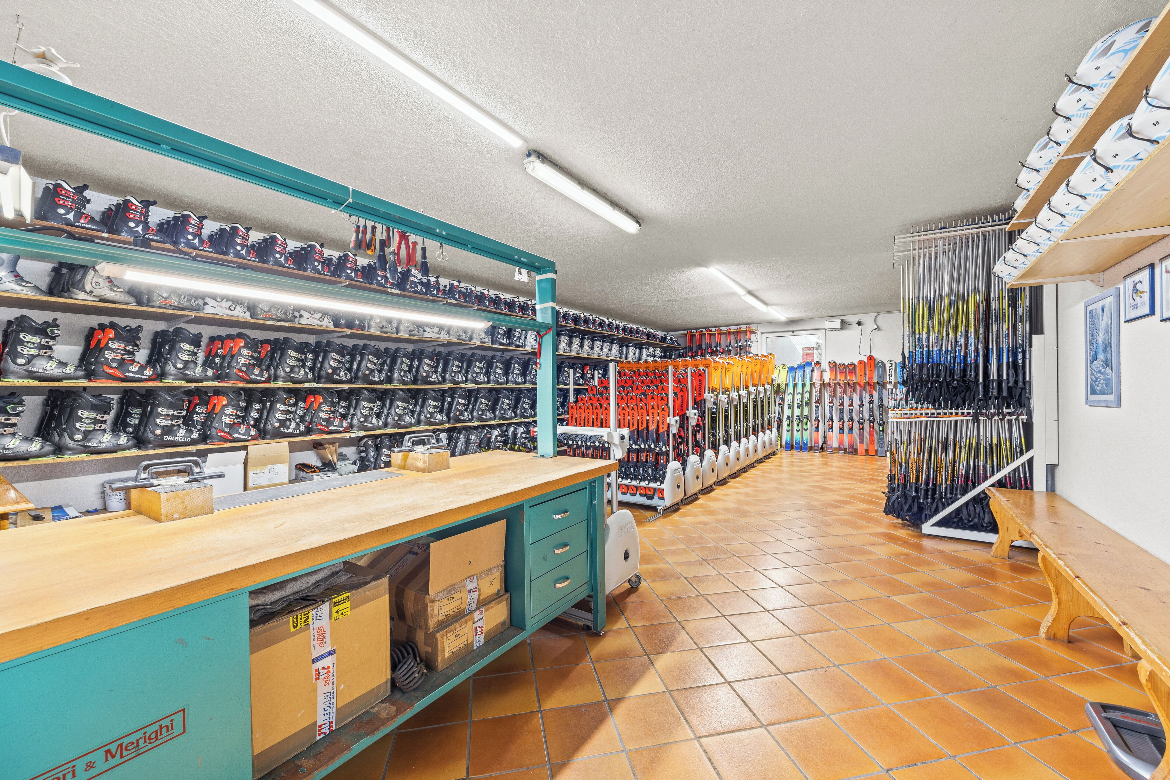 A shoe store with multiple shelves of footwear, a wooden counter, and a tiled floor.