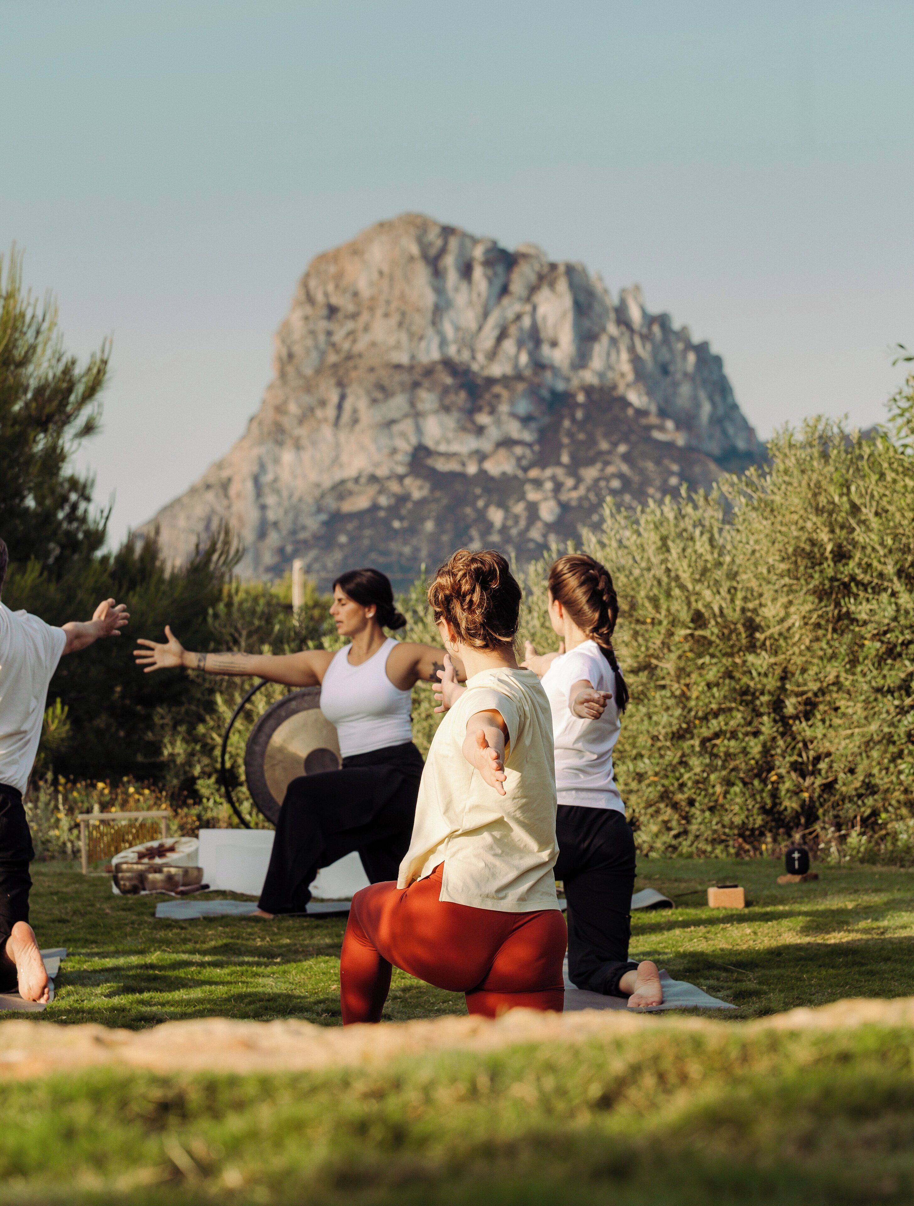 A group of people exercising outdoors with a mountainous backdrop.