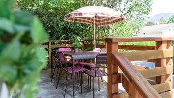 Un patio al aire libre con una terraza de madera, una mesa y sillas.