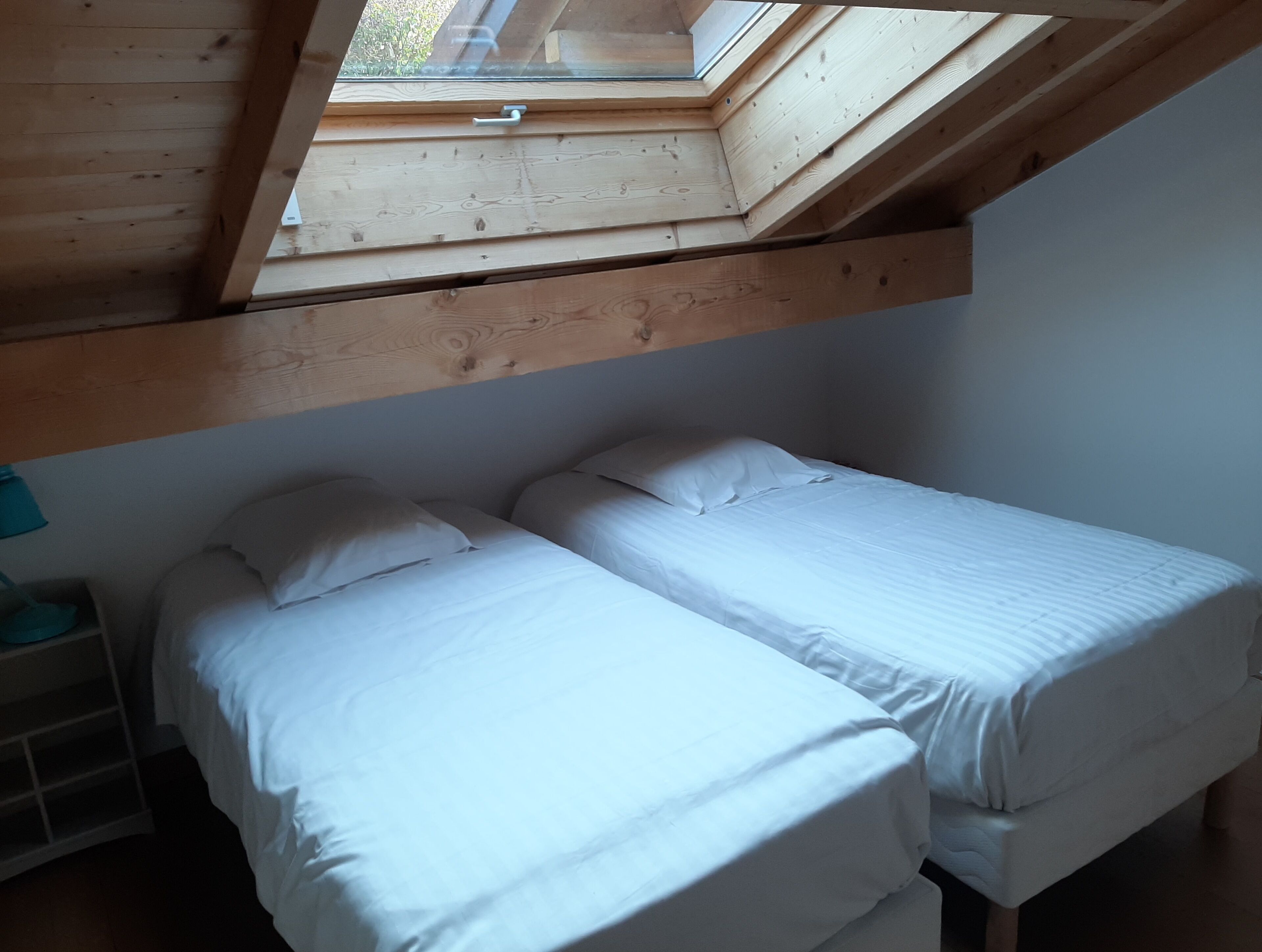 Un dormitorio con dos camas, un tragaluz y techo de madera.