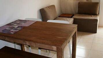 A room with a wooden table, a sofa, and a small side table.