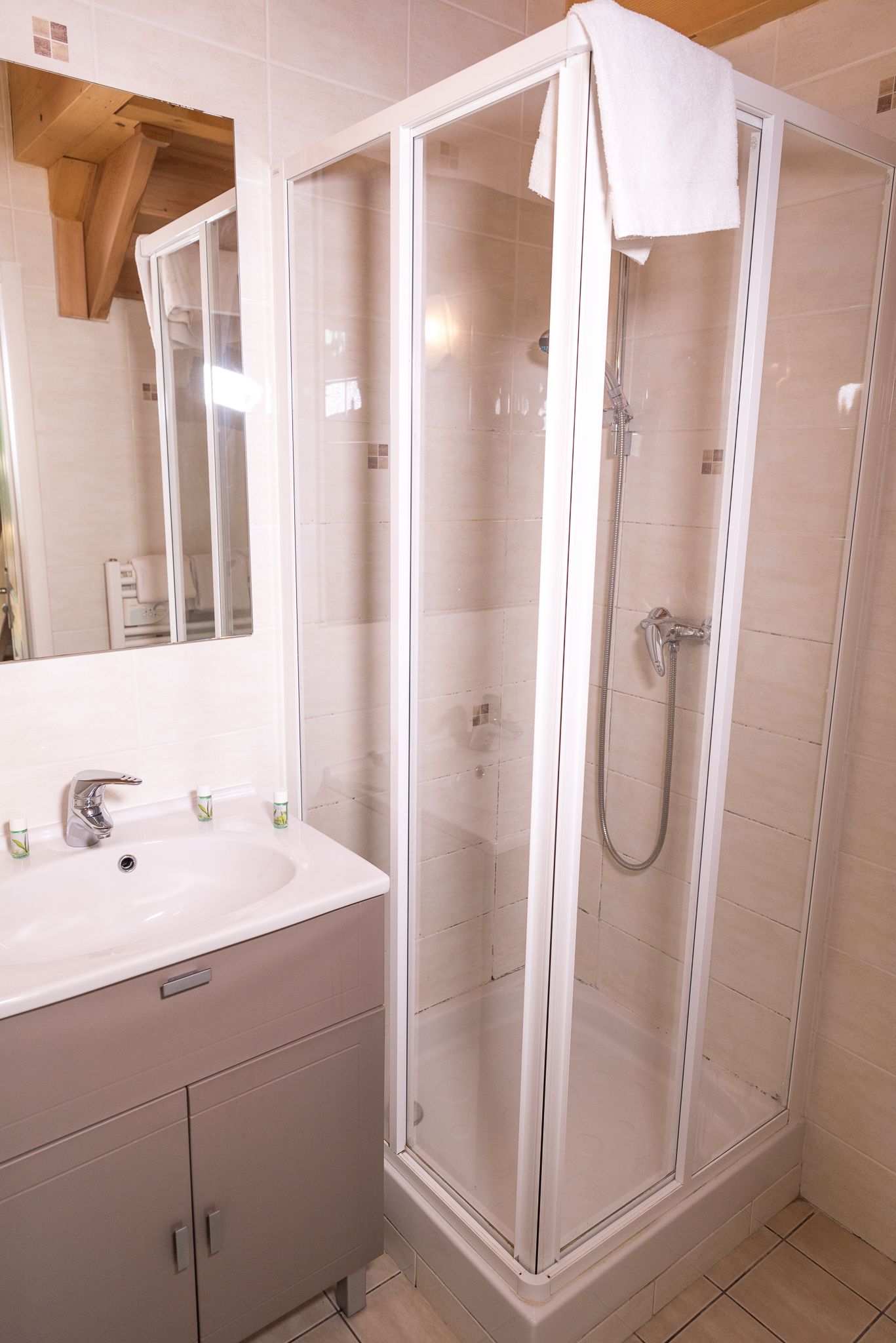 Un baño con ducha envuelta en vidrio, un lavamanos con espejo y armarios.