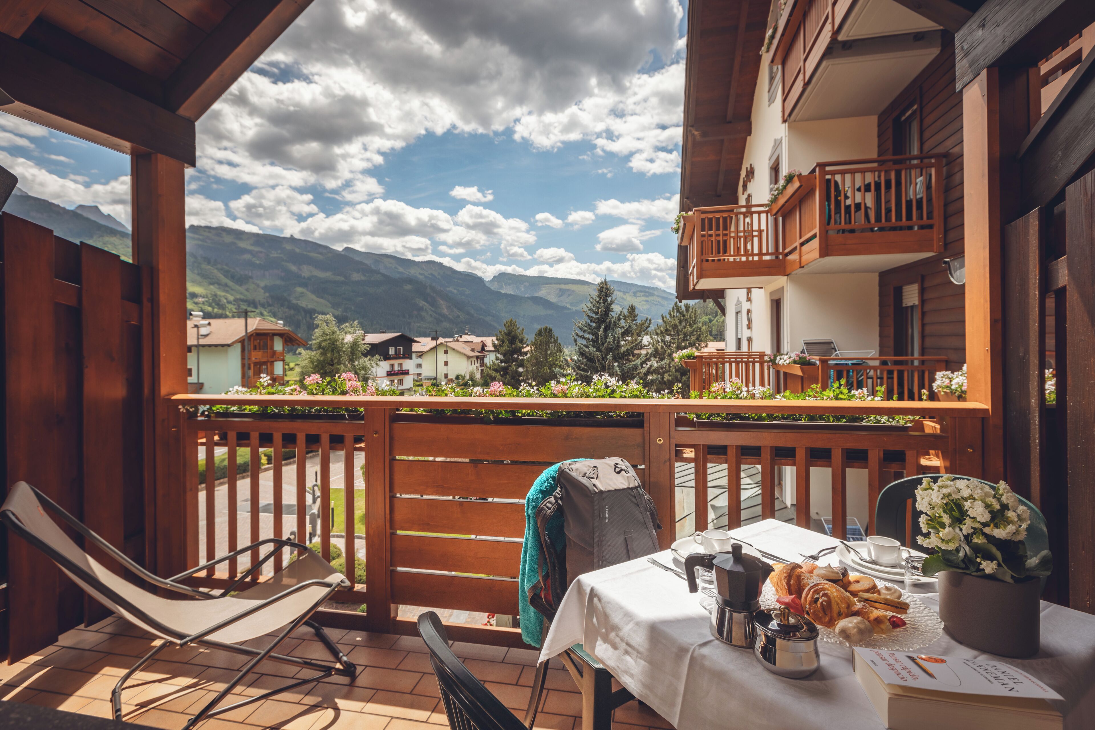 Un balcón con una mesa lista para el desayuno, una silla y vistas a las montañas.