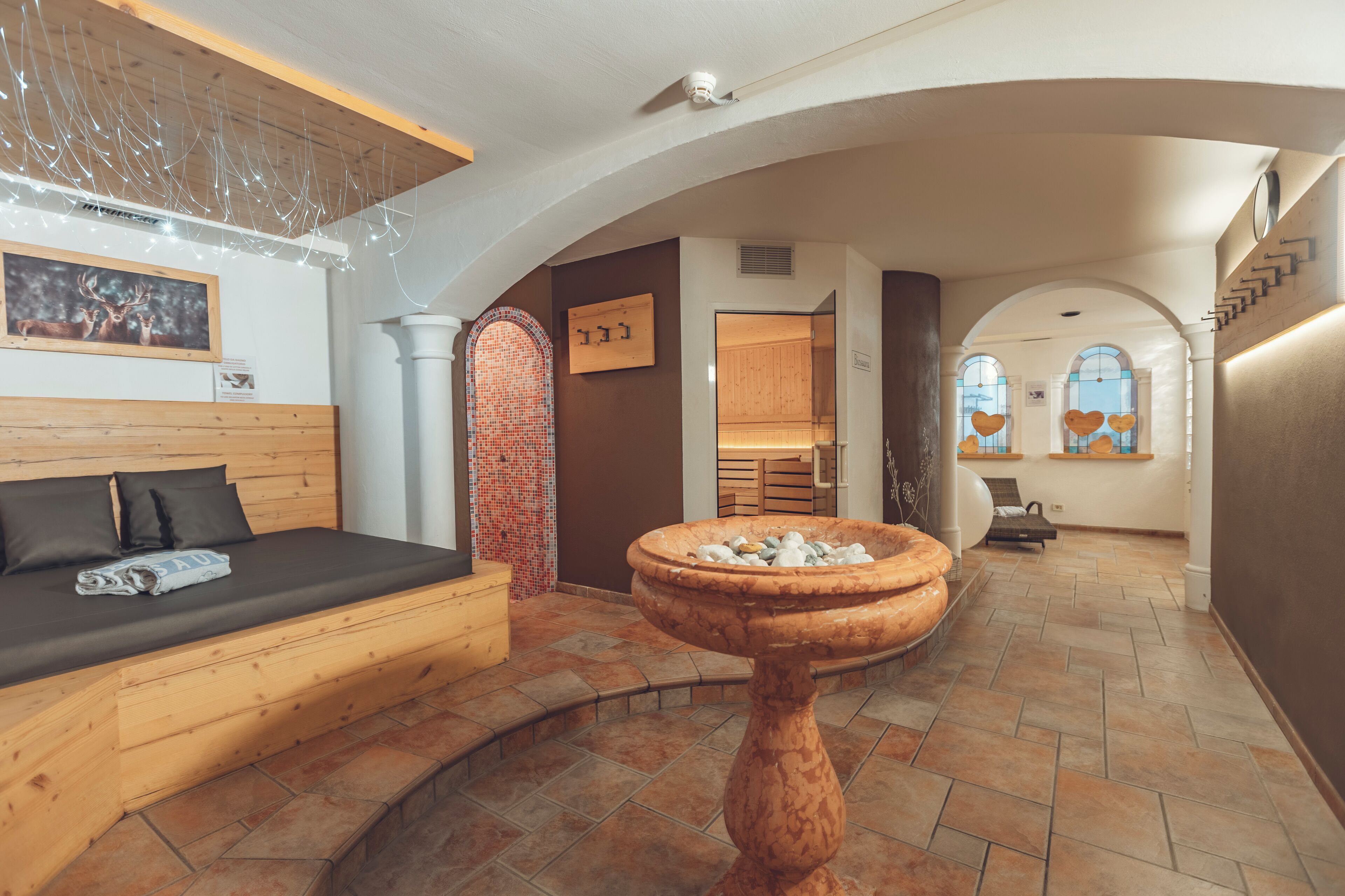 Une pièce chaleureuse avec un lit en bois, une fontaine en pierre et une vue sur un intérieur rustique.