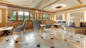 A spacious room with a checkered floor, large windows with curtains, a seating area with a sofa and chairs, and a table with a vase. - Aparthotel Majestic (Predazzo)