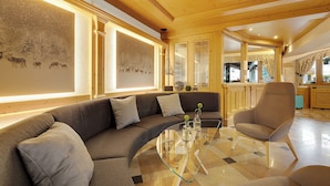 A modern living room with a curved glass coffee table, a sofa, and a chair. - Aparthotel Majestic (Predazzo)