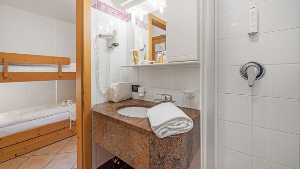 A bathroom with a wooden bunk bed, a sink with a towel, and a mirror. - Aparthotel Majestic (Predazzo)