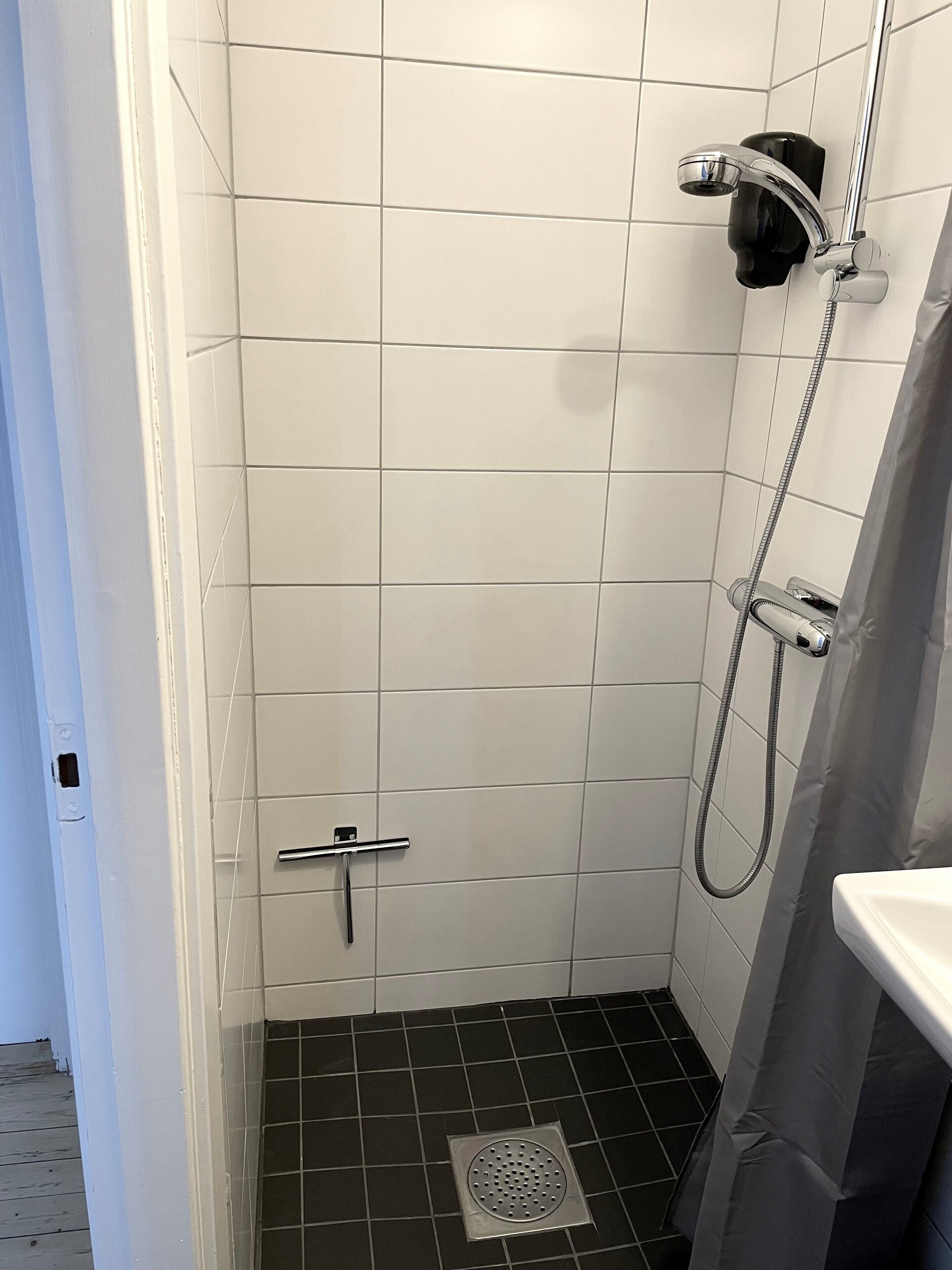 Un espacio de ducha pequeño con azulejos, una ducha de mano y un grifo de mano.