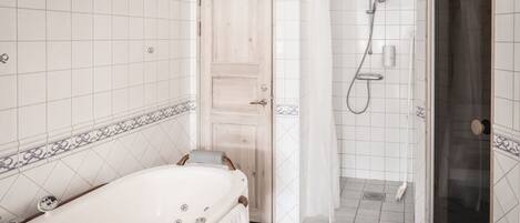 Un baño con bañera, ducha y paredes de azulejos.