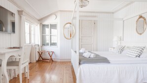 A bedroom with a four-poster bed, a desk with a chair, a mirror, and a window. - Klockargården Hotell (Tallberg)