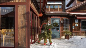 A wooden building with a reception area, large windows, and a snow-covered ground. - Klockargården Hotell (Tallberg)
