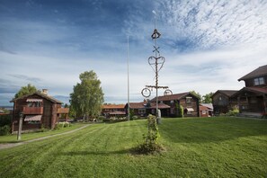 Una casa de madera rústica con un césped cuidado y una alta estructura metálica decorativa en el centro.