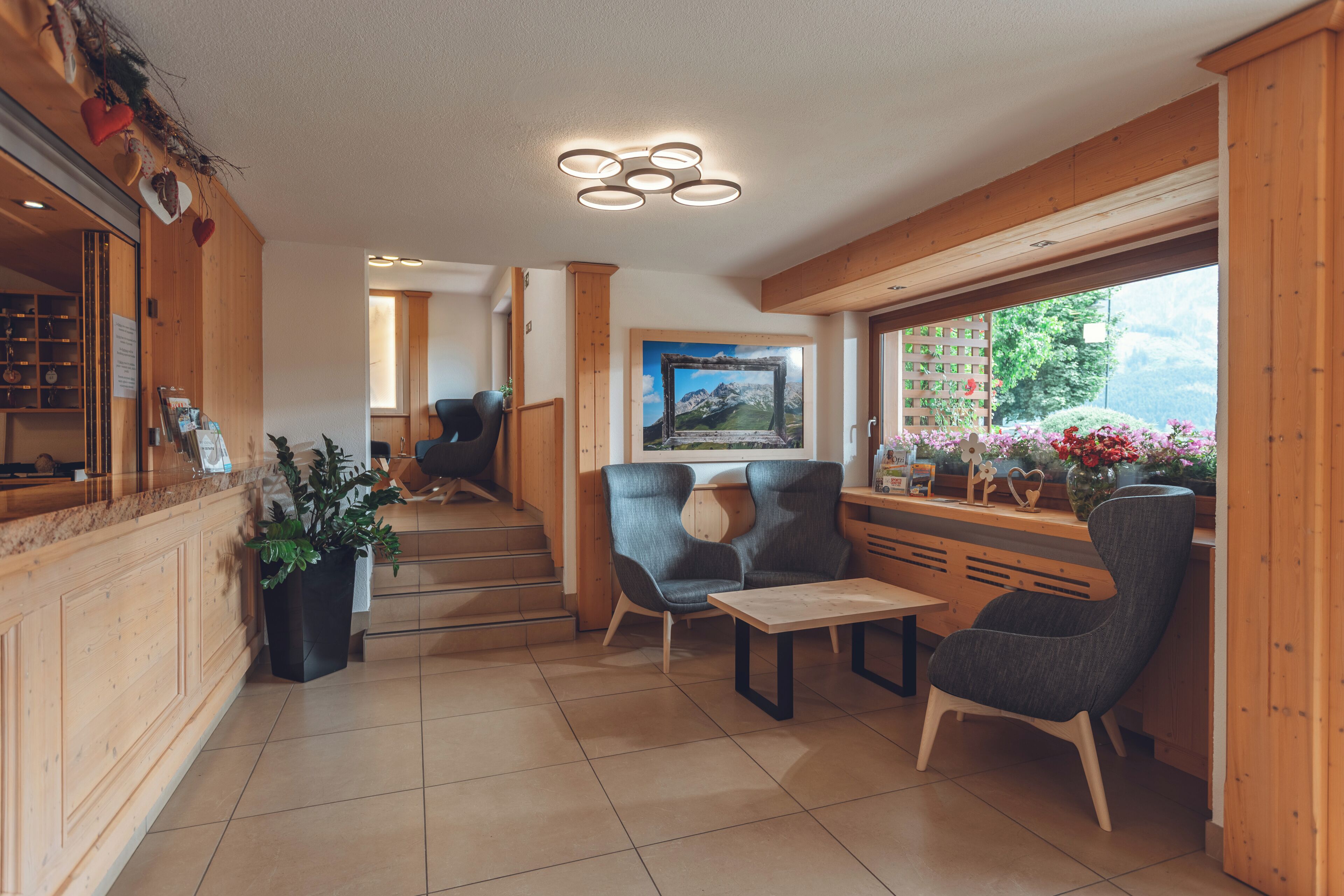 A cozy interior with a wooden staircase, seating area, and a view of greenery outside.