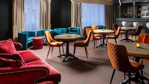 Et hotellobby med barområde, siddepladser og store vinduer.