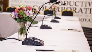 A conference table with microphones, a vase of flowers, and documents. - Mercure Chisinau Center Jazz Hotel (Chisinau)
