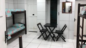A room with a bunk bed, a table with chairs, a mirror, and a wardrobe. - Pousada Suites do Pelo (Salvador)