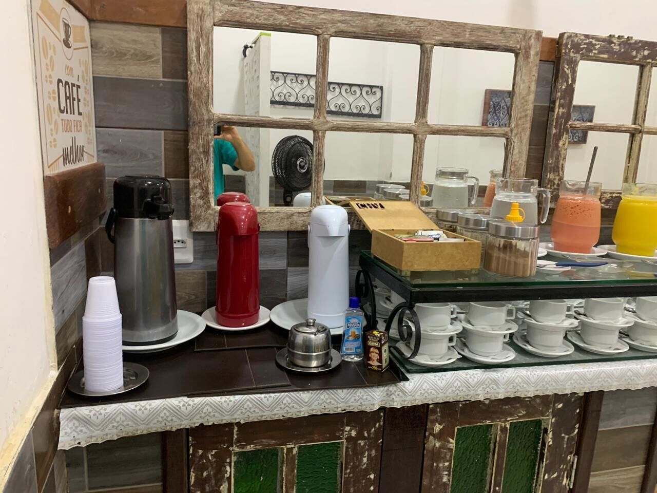 A kitchen counter with coffee-making equipment, disposable cups, and a variety of food items.