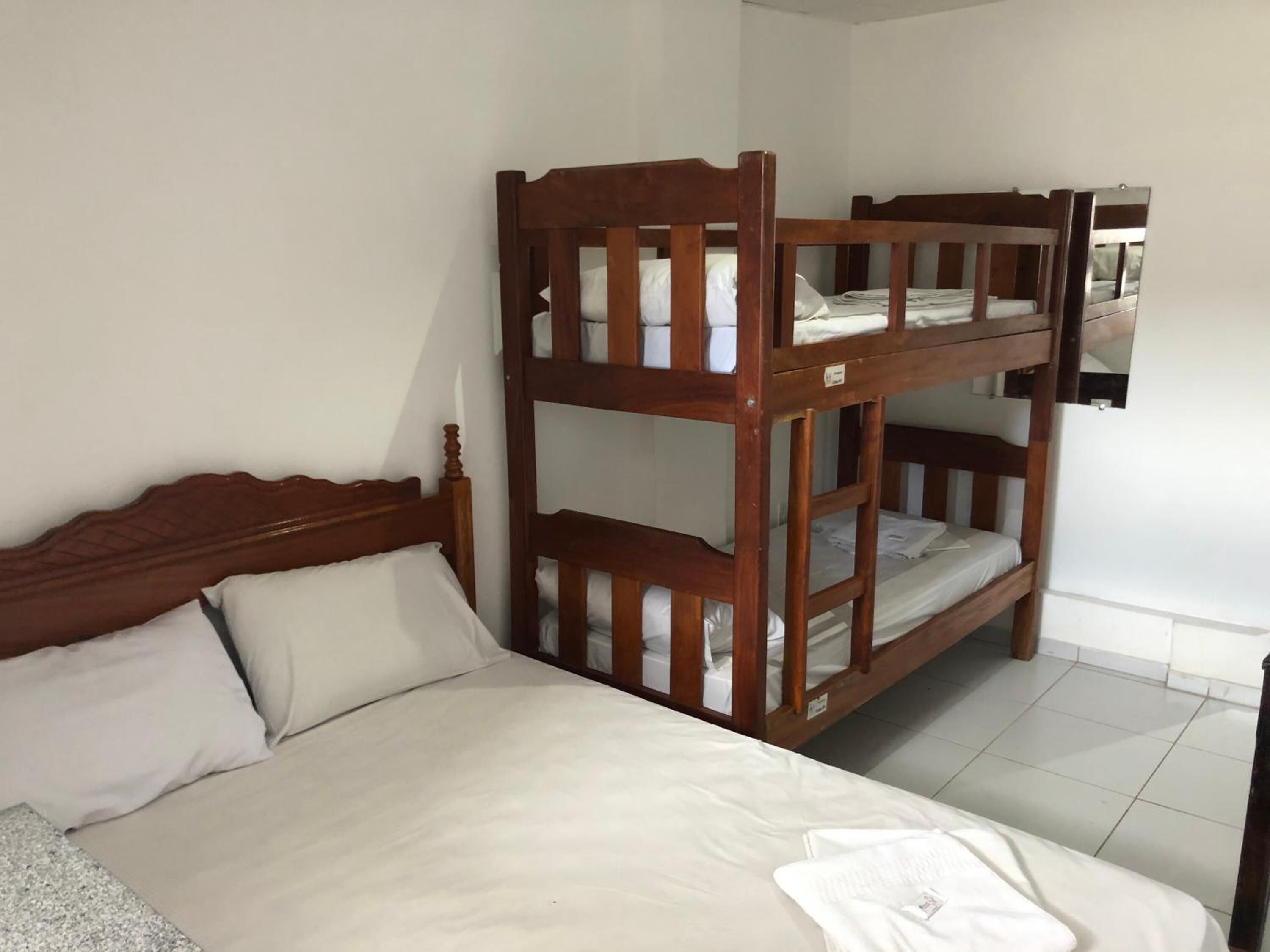 A bunk bed room with a wooden headboard and a single bed with white bedding.